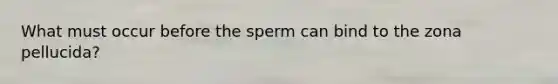 What must occur before the sperm can bind to the zona pellucida?