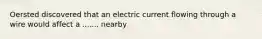 Oersted discovered that an electric current flowing through a wire would affect a ....... nearby