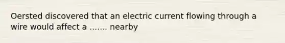 Oersted discovered that an electric current flowing through a wire would affect a ....... nearby