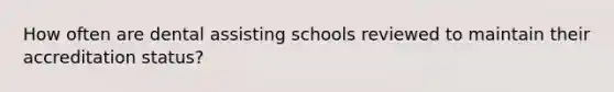 How often are dental assisting schools reviewed to maintain their accreditation status?