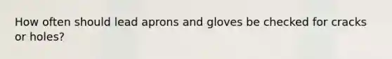 How often should lead aprons and gloves be checked for cracks or holes?