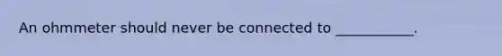 An ohmmeter should never be connected to ___________.