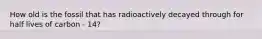 How old is the fossil that has radioactively decayed through for half lives of carbon - 14?