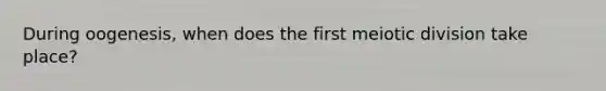 During oogenesis, when does the first meiotic division take place?