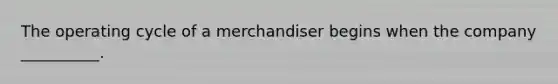 The operating cycle of a merchandiser begins when the company __________.