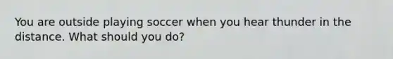 You are outside playing soccer when you hear thunder in the distance. What should you do?