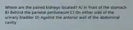 Where are the paired kidneys located? A) In front of the stomach B) Behind the parietal peritoneum C) On either side of the urinary bladder D) Against the anterior wall of the abdominal cavity