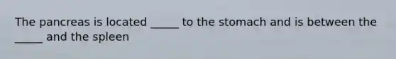 The pancreas is located _____ to the stomach and is between the _____ and the spleen