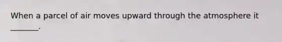 When a parcel of air moves upward through the atmosphere it _______.