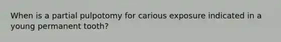 When is a partial pulpotomy for carious exposure indicated in a young permanent tooth?