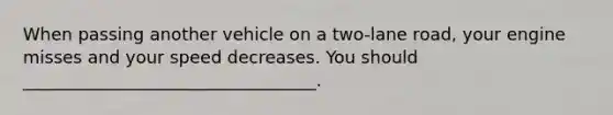 When passing another vehicle on a two-lane road, your engine misses and your speed decreases. You should __________________________________.