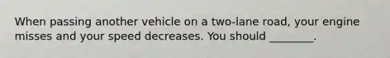 When passing another vehicle on a two-lane road, your engine misses and your speed decreases. You should ________.