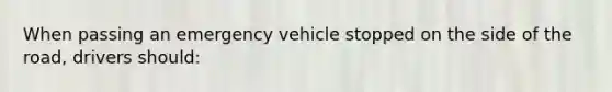 When passing an emergency vehicle stopped on the side of the road, drivers should: