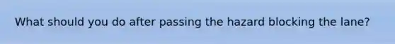 What should you do after passing the hazard blocking the lane?