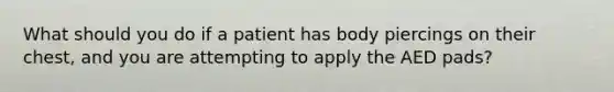 What should you do if a patient has body piercings on their chest, and you are attempting to apply the AED pads?