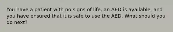 You have a patient with no signs of life, an AED is available, and you have ensured that it is safe to use the AED. What should you do next?