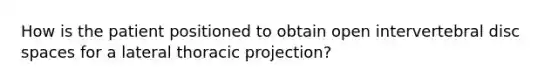 How is the patient positioned to obtain open intervertebral disc spaces for a lateral thoracic projection?