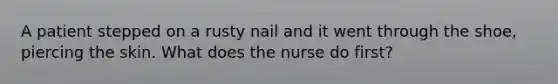 A patient stepped on a rusty nail and it went through the shoe, piercing the skin. What does the nurse do first?