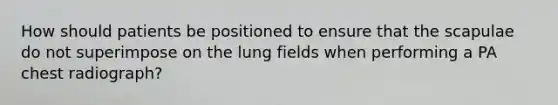 How should patients be positioned to ensure that the scapulae do not superimpose on the lung fields when performing a PA chest radiograph?