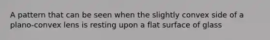 A pattern that can be seen when the slightly convex side of a plano-convex lens is resting upon a <a href='https://www.questionai.com/knowledge/kOWiejdjxQ-flat-surface' class='anchor-knowledge'>flat surface</a> of glass