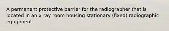 A permanent protective barrier for the radiographer that is located in an x-ray room housing stationary (fixed) radiographic equipment.