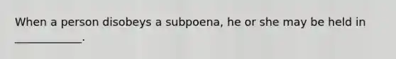 When a person disobeys a subpoena, he or she may be held in ____________.