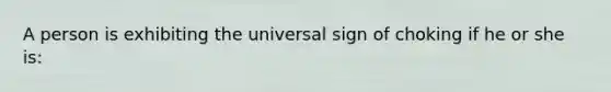 A person is exhibiting the universal sign of choking if he or she is: