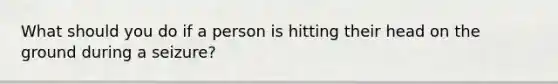 What should you do if a person is hitting their head on the ground during a seizure?