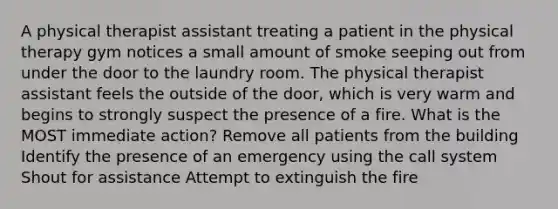 A physical therapist assistant treating a patient in the physical therapy gym notices a small amount of smoke seeping out from under the door to the laundry room. The physical therapist assistant feels the outside of the door, which is very warm and begins to strongly suspect the presence of a fire. What is the MOST immediate action? Remove all patients from the building Identify the presence of an emergency using the call system Shout for assistance Attempt to extinguish the fire