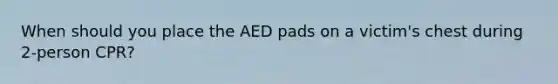 When should you place the AED pads on a victim's chest during 2-person CPR?