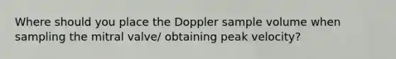 Where should you place the Doppler sample volume when sampling the mitral valve/ obtaining peak velocity?