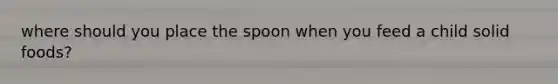 where should you place the spoon when you feed a child solid foods?