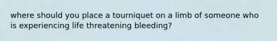 where should you place a tourniquet on a limb of someone who is experiencing life threatening bleeding?