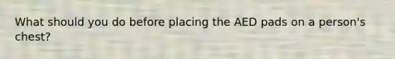 What should you do before placing the AED pads on a person's chest?