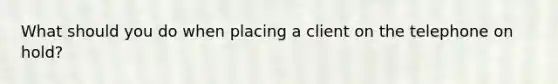 What should you do when placing a client on the telephone on hold?