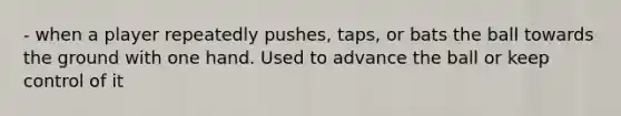 - when a player repeatedly pushes, taps, or bats the ball towards the ground with one hand. Used to advance the ball or keep control of it