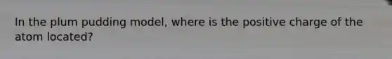 In the plum pudding model, where is the positive charge of the atom located?