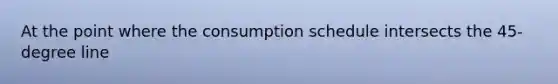 At the point where the consumption schedule intersects the 45-degree line