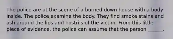 The police are at the scene of a burned down house with a body inside. The police examine the body. They find smoke stains and ash around the lips and nostrils of the victim. From this little piece of evidence, the police can assume that the person ______.