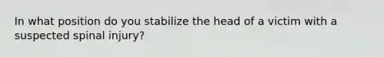 In what position do you stabilize the head of a victim with a suspected spinal injury?