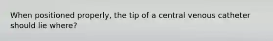 When positioned properly, the tip of a central venous catheter should lie where?