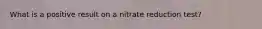 What is a positive result on a nitrate reduction test?