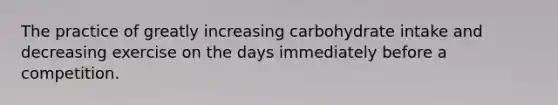 The practice of greatly increasing carbohydrate intake and decreasing exercise on the days immediately before a competition.