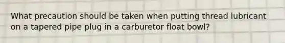 What precaution should be taken when putting thread lubricant on a tapered pipe plug in a carburetor float bowl?