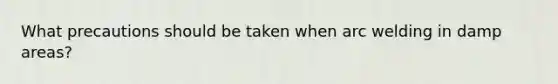 What precautions should be taken when arc welding in damp areas?