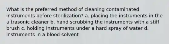 What is the preferred method of cleaning contaminated instruments before sterilization? a. placing the instruments in the ultrasonic cleaner b. hand scrubbing the instruments with a stiff brush c. holding instruments under a hard spray of water d. instruments in a blood solvent