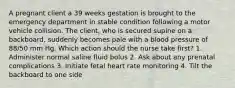 A pregnant client a 39 weeks gestation is brought to the emergency department in stable condition following a motor vehicle collision. The client, who is secured supine on a backboard, suddenly becomes pale with a blood pressure of 88/50 mm Hg. Which action should the nurse take first? 1. Administer normal saline fluid bolus 2. Ask about any prenatal complications 3. Initiate fetal heart rate monitoring 4. Tilt the backboard to one side