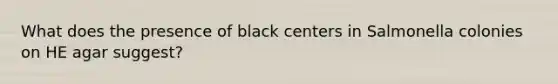 What does the presence of black centers in Salmonella colonies on HE agar suggest?