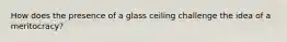 How does the presence of a glass ceiling challenge the idea of a meritocracy?