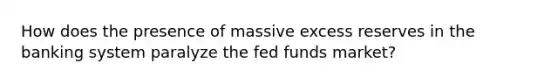 How does the presence of massive excess reserves in the banking system paralyze the fed funds market?